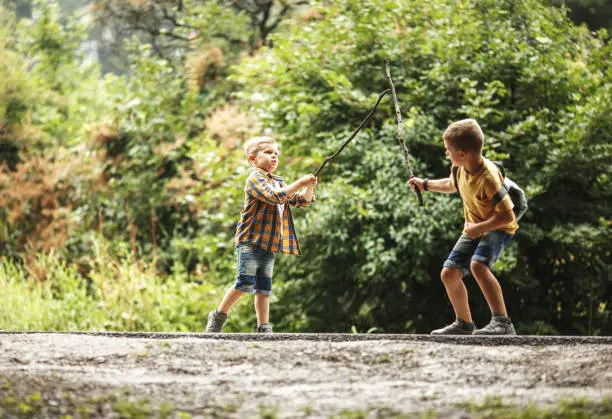 Two boys playing fight with wooden swords.Childhood concept.