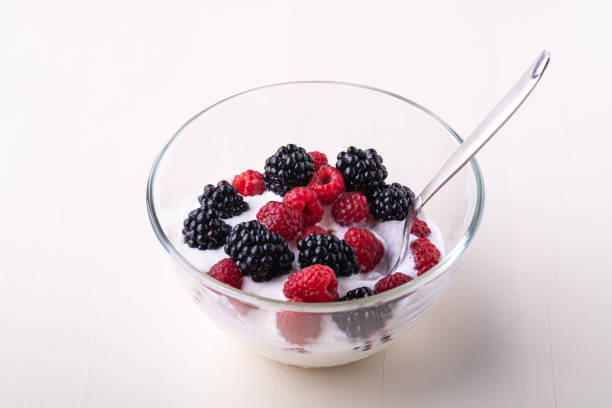 istock Ice cream with raspberry, blackberry berries with spoon in glass bowl on white background 1164694584