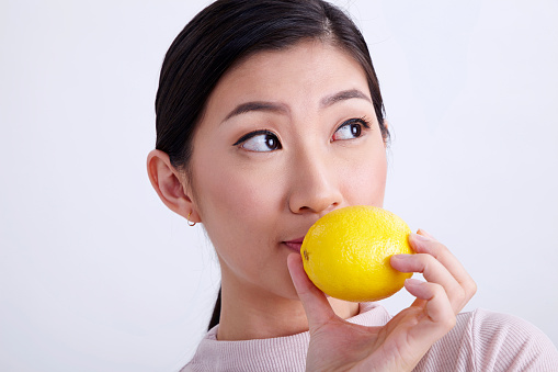 chinese women holding whole lemon on the white background