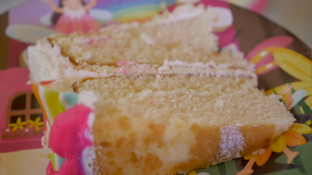 Close up of a slice of white cake with colorful rainbow frosting on a plate