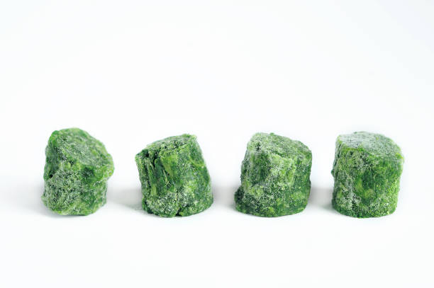 istock Frozen spinach on a white background. Spinach has the shape of a washer. Washers laid out in a row. 1164701935