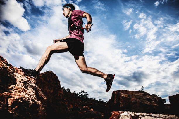 istock trail runner jumping on the horizon and stone 1164702878