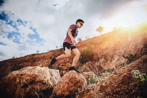 istock trail runner jumping on the horizon and stone 1164702990