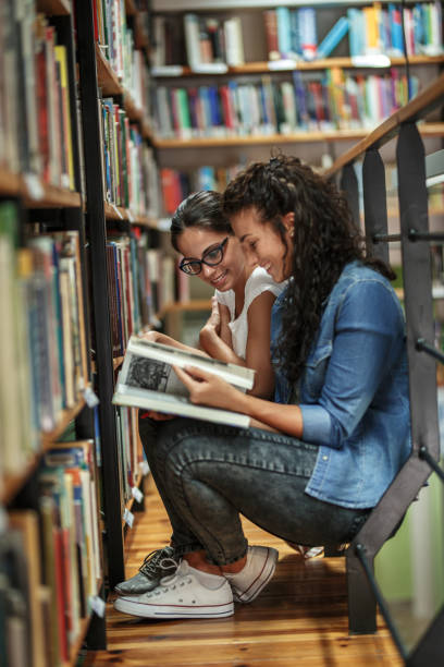 istock Two female students read and learns by the book shelf at the library. 1164703447