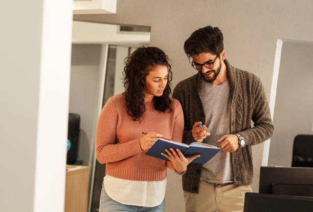 istock Two office workers discuss about new project.They looking in notebook and talking. 1164703489