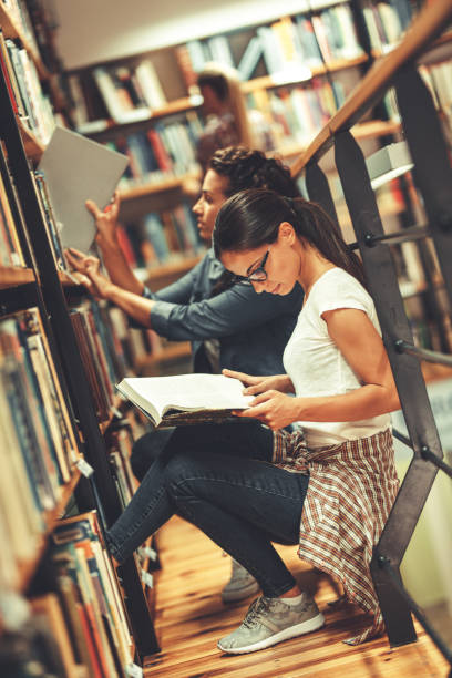 istock Two female students read and learns by the book shelf at the library. 1164703492