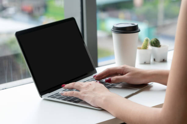 istock Young business woman using laptop computer while sitting at cafe table next to office windows. 1164705843