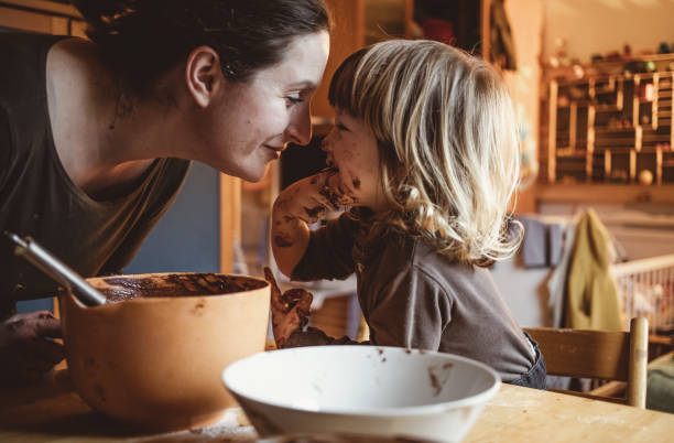 kleinkind macht kekse mit seiner mutter - kuchen backen stock-fotos und bilder