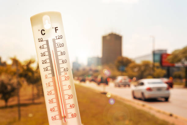Thermometer in front of cars and traffic during heatwave stock photo