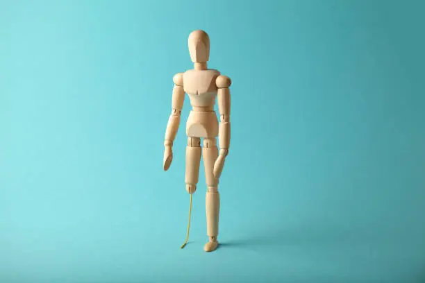 Wooden figure of man with artificial prosthetic leg. Amputee and disability concept.