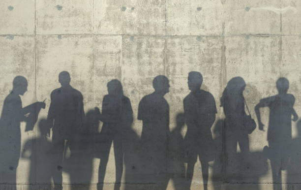 istock Group of people walking in a relaxed pose cast a shadow on the concrete wall. Conceptual creative illustration with silhouettes of men and women. Copy space. 3D rendering. 1164708053