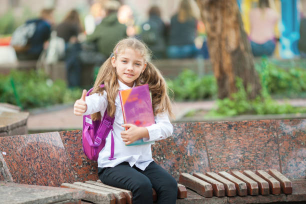 istock Schoolgirl with a backpack and book outdoors. Education and learning concept. 1164709096