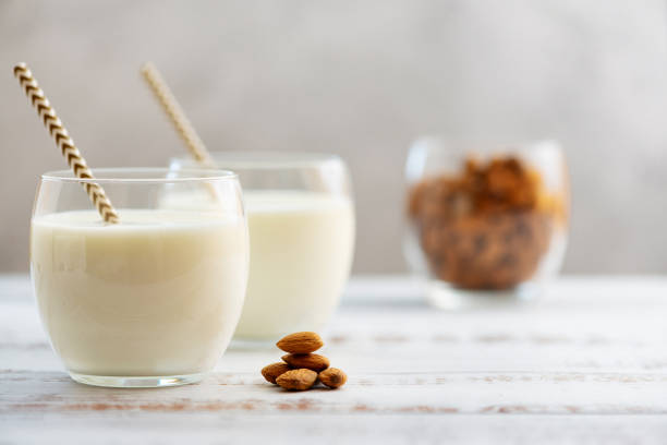 Almond milk in glasses with almond on a light wooden table stock photo