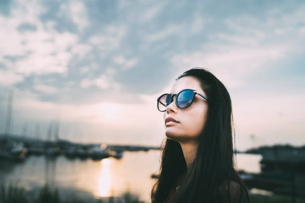 Girl in sunglasses posing in front of a cloudy sky