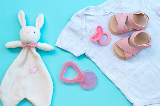 istock Baby clothes, shoes, teether and pacifier on a blue background 1164717185