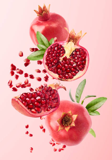 Flying in air fresh ripe whole and cut pomegranate with seeds and leaves stock photo