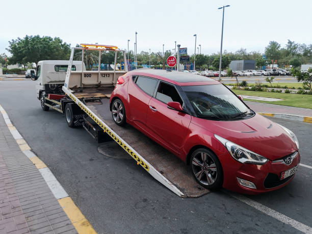 una grúa (transportador de coches, camión) que transporta un coche para repararlo en la calle de la ciudad - towing away fotografías e imágenes de stock