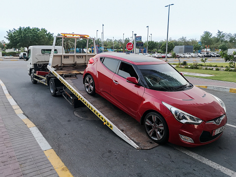 A tow truck (car transporter, lorry) carrying a car for repairing at the city street
- Abu Dhabi, UAE July 07, 2019