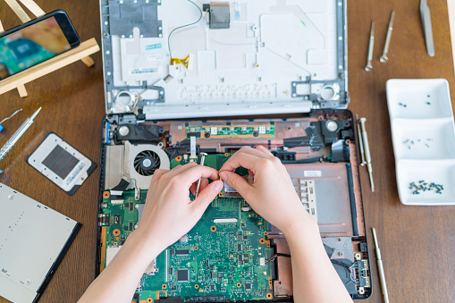 A young woman is fixing a broken laptop to reduce rubbish and support zero waste at home. Point of view photo.