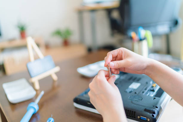 A young woman is fixing a broken laptop to reduce rubbish and support zero waste at home.