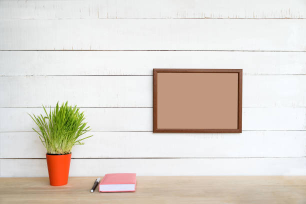 istock Empty frame on a white wall. Notebook and pen, green houseplant on the table. Working space at home 1164727838