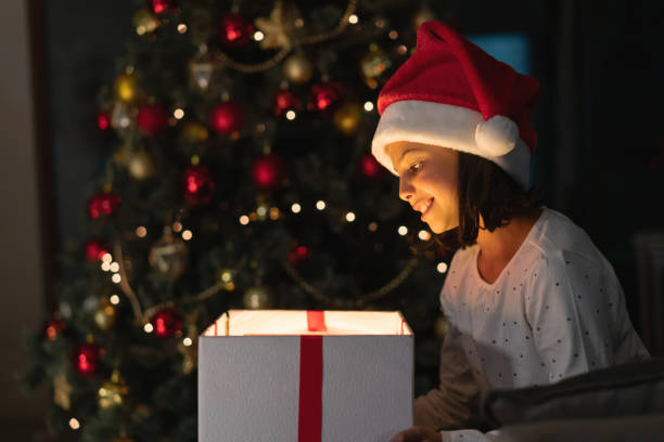 istock Happy girl opening a present on Christmas Eve 1164731579