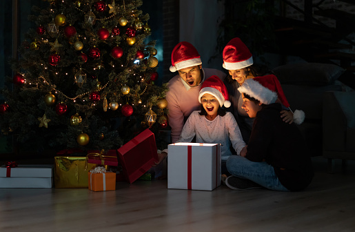 Portrait of an excited family opening Christmas gifts at home and looking very happy â holidays concepts