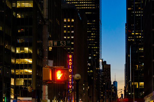 New York, New York, USA - November 2018: red traffic light and Radio City Music Hall in Manhattan night. People and traffic can be seen around this iconic location at night.