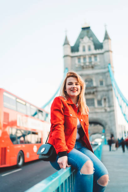 istock Smiling young woman traveler in red jacket visiting Tower Bridge 1164733061