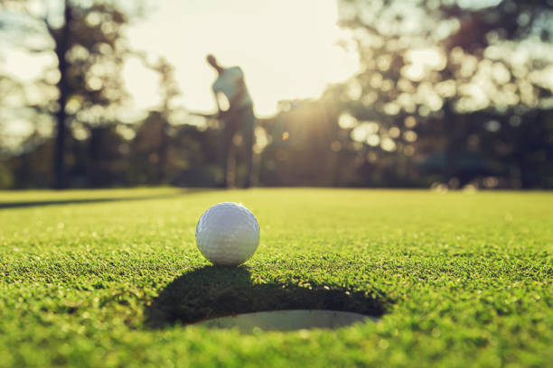 istock golf player putting golf ball into hole 1164735756