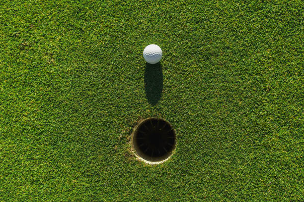 istock golf ball on green grass with hole and sunlight 1164735757