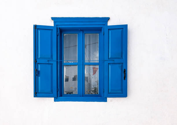 ventana azul con persianas abiertas y pared blanca de casa griega en amorgos, grecia. - wood window fotografías e imágenes de stock