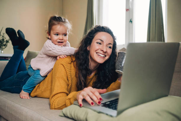 istock Mother and daughter using laptop on sofa 1164740665