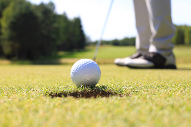 istock Golf player at the putting green hitting ball into a hole. 1164749699