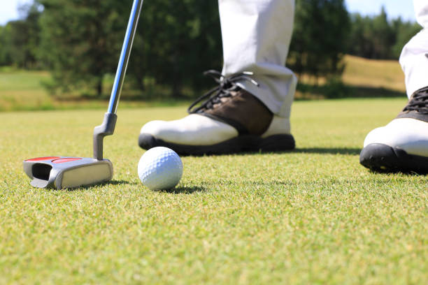 istock Golf player at the putting green hitting ball into a hole. 1164749968
