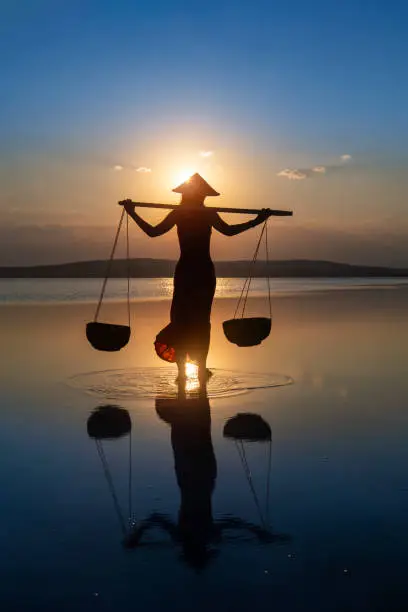 Photo of Woman farmer carrying baskets on the water.