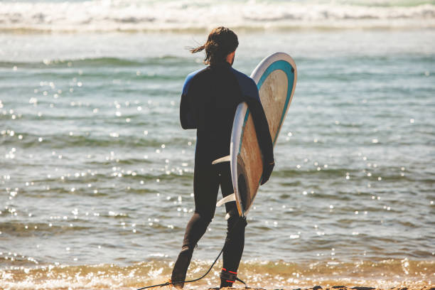 istock Man with surfboard at the beach 1164757441