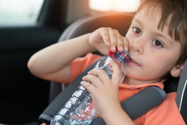 água bebendo do rapaz pequeno no assento de segurança do carro - water child bottle little boys - fotografias e filmes do acervo