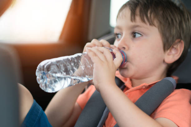 istock Little boy drinking water in car safety seat 1164758755