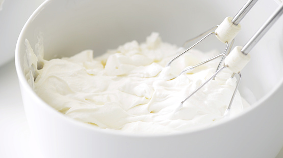 Close up scene of mixer and cream in a bowl
