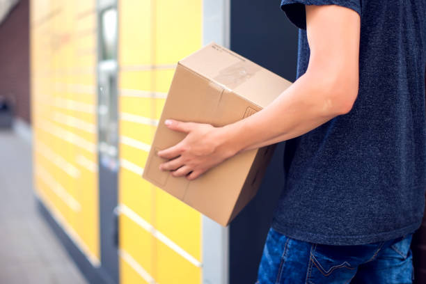 istock Man client using automated self service post terminal machine or locker to deposit the parcel for storage 1164758868