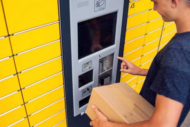 istock Client using automated self service post terminal machine or locker to deposit a parcel for storage 1164760387
