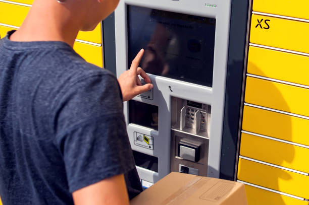 istock Client using automated self service post terminal machine or locker to deposit a parcel for storage 1164760388