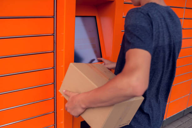 istock Client using automated self service post terminal machine or locker to deposit a parcel for storage 1164760389
