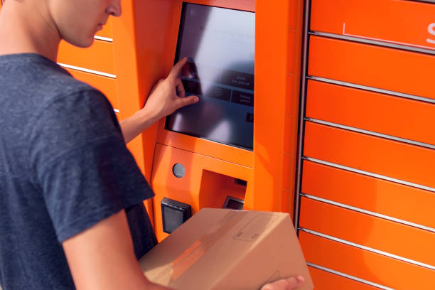 istock Client using automated self service post terminal machine or locker to deposit a parcel for storage 1164760395