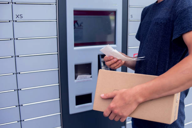 istock Client using automated self service post terminal machine or locker to deposit a parcel for storage 1164760398