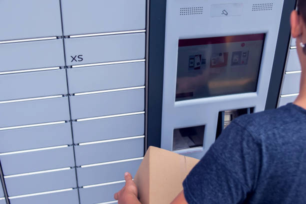 istock Client using automated self service post terminal machine or locker to deposit a parcel for storage 1164760404