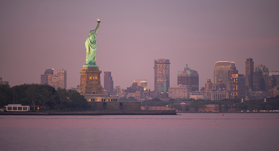 The Statue of Liberty after sunset with Brooklyn New York in the background