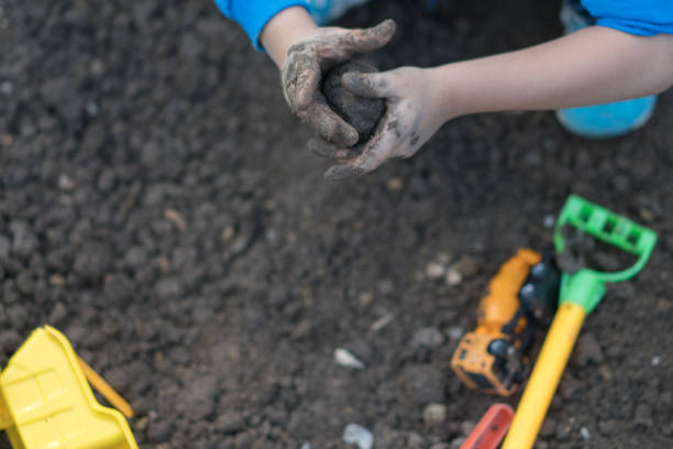 istock Happy boy plays in the mud with his toy 1164760719