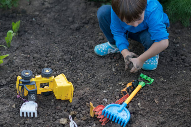 Happy boy plays in the mud with his toy